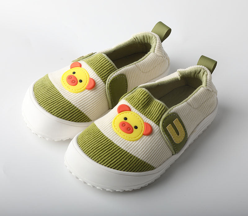 Pair of green and beige children's shoes with cartoon duck face design on a light gray background